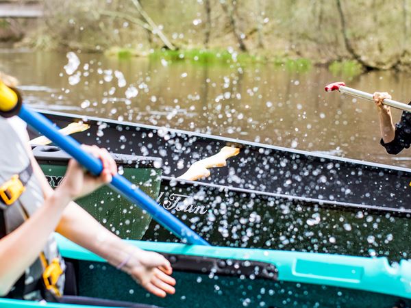 Brother and Sister splashing each other with water using their kayak paddles