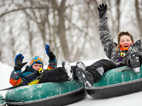 Children snowtubing and smiling